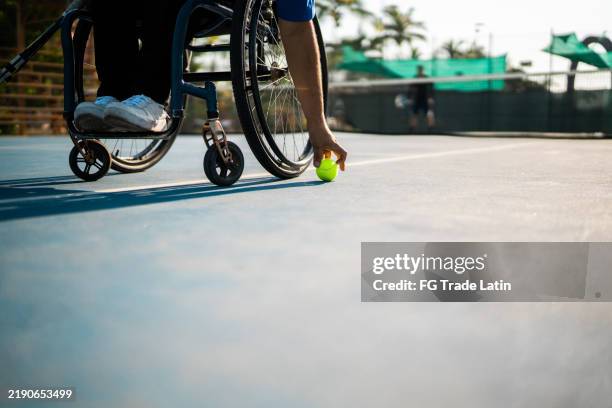 wheelchair tennis player man taking the ball at tennis court - wheelchair tennis stock pictures, royalty-free photos & images