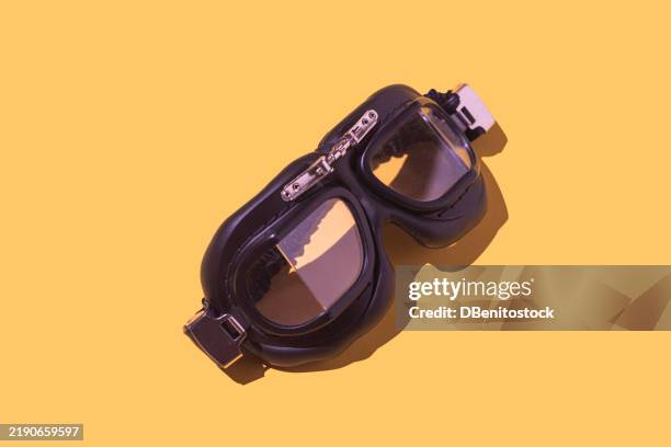 old aviation goggles on yellow background. vintage, aviation, glasses, retro style, protective glasses, minimalism, pilot equipment, antique design, aeronautical accessory, yellow background - occhiali da aviatore foto e immagini stock