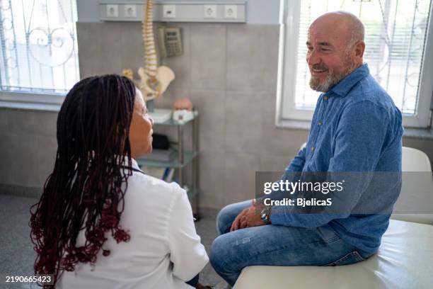 doctor and patient talking at doctor's office - cuidados de saúde primários imagens e fotografias de stock