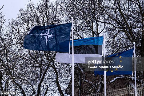 Estonian and EU flags fly over the Narva crossing at the Estonian-Russian border in Narva on December 15, 2024. In heavy snowfall and high winds,...