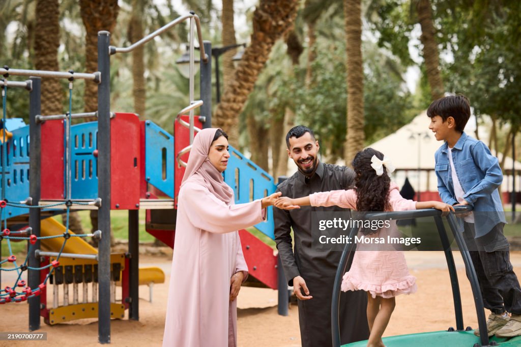 Man and woman with children playing at playground