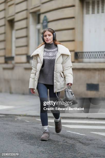 Diane Batoukina wears black headphones Airpods Max from Apple, a grey and white sweater, grey legging, a cream Varley bomber jacket, a grey leather...