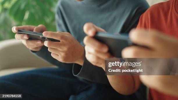 mature et adolescent jouant à un jeu sur smartphone à la maison. - jeu mobile photos et images de collection