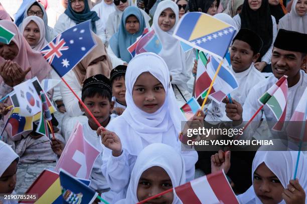 Children hold national flags during prayers at the Baiturrahman Grand Mosque for those who lost their lives in the 2004 Indian Ocean tsunami in Banda...