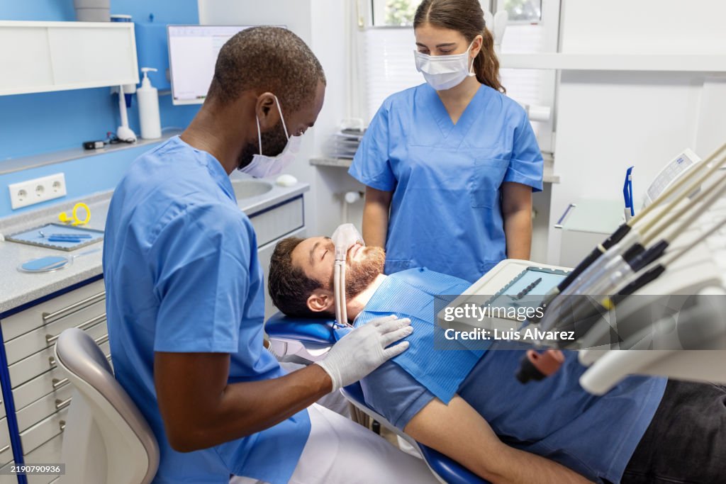 Use of nitrous oxide gas known as laughing gas to calm down patient during dental surgery.