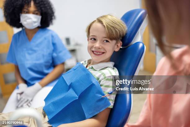 happy young boy smiling at his mother after a dental procedure - odontopediatría fotografías e imágenes de stock