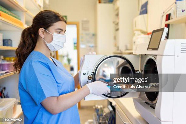 dental assistant using autoclave for medical instrument sterilization - disinfection stock pictures, royalty-free photos & images