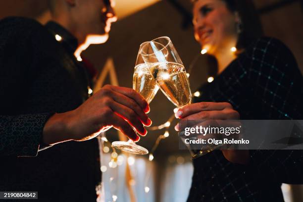 couple clinking champagne flutes celebrating new year's eve - champagnerglas stock-fotos und bilder
