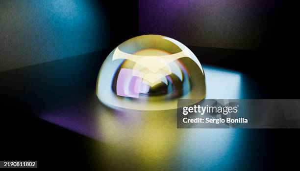 a colorful, iridescent glass paperweight reflects light on a smooth surface with a dark background - study room background stock illustrations
