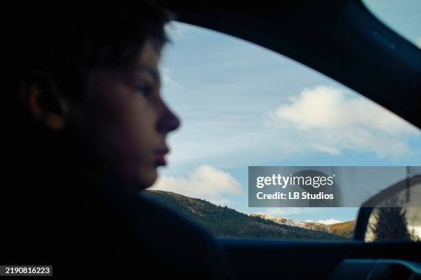 close-up side profile of a child looking out a car window with a scenic view of mountains and blue sky in the background, highlands, scotland - car side profile people stock pictures, royalty-free photos & images