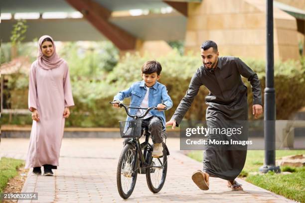 un garçon apprend à faire du vélo sur le sentier du parc - culture saoudienne photos et images de collection