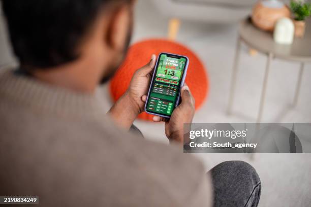 hombre comprobando los resultados deportivos en la pantalla del dispositivo móvil - apuestas deportivas fotografías e imágenes de stock