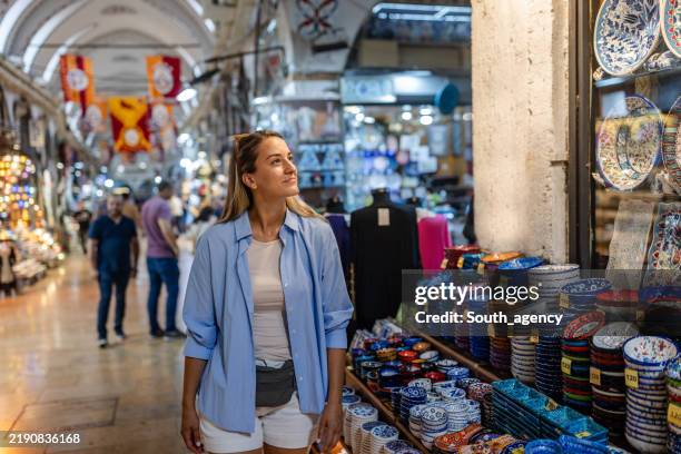woman explores vibrant market with pottery display. - grand bazaar istanbul stock pictures, royalty-free photos & images