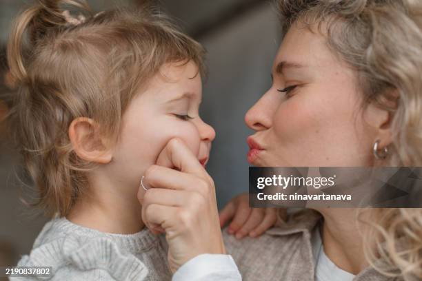 close-up of a woman pinching her daughter's cheek and puckering her lips - pinch face stock pictures, royalty-free photos & images