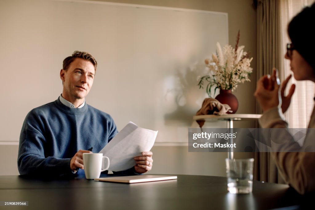 Male business professional taking interview of female candidate in office