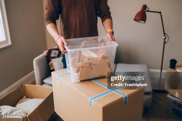 man packing household belongings in cardboard boxes for moving day - storage compartment stock pictures, royalty-free photos & images