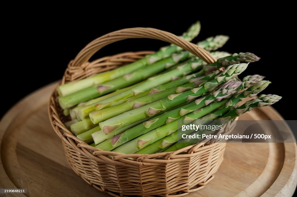 A photo of fresh green asparagus in a basket,Isolated on a black background