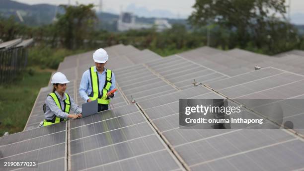the solar farm(solar panel) with two engineers walk to check the operation of the system - lucht en ruimtevaartingenieur stockfoto's en -beelden