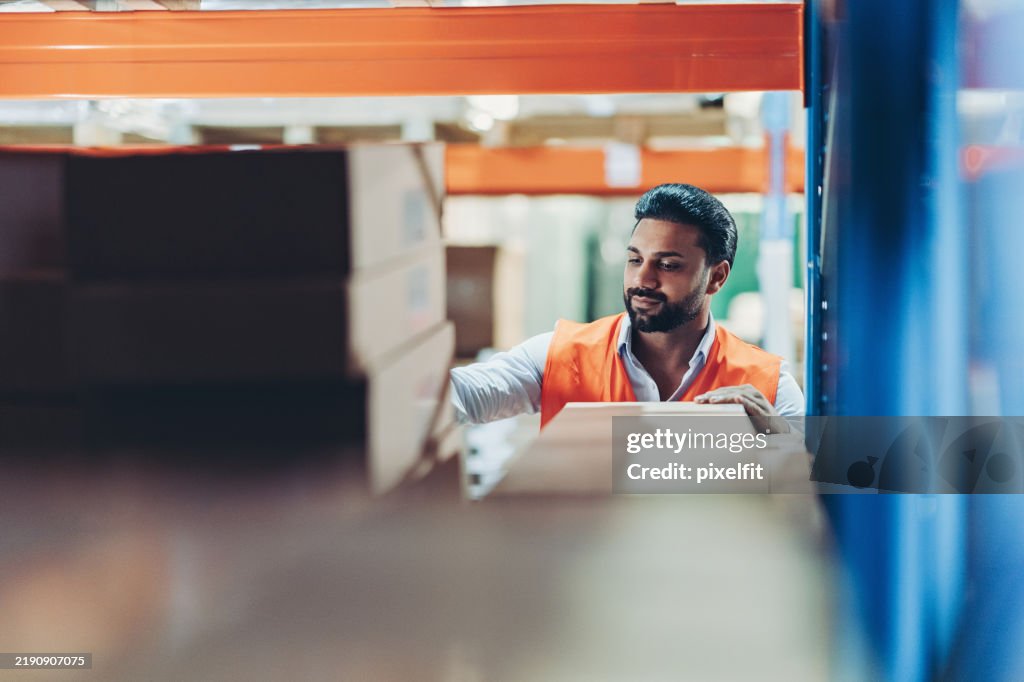 Junger männlicher Lagerarbeiter sortiert Pakete in einem Lager