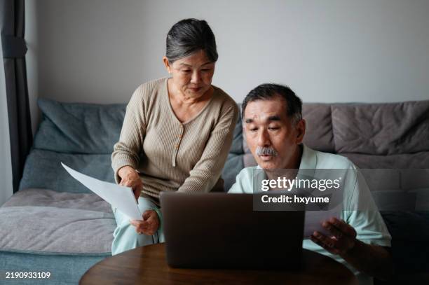 senior couple managing finances at home - pens