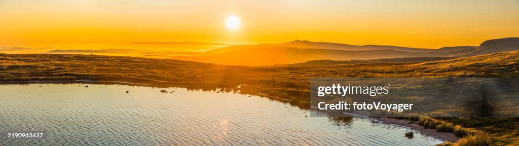 Golden sunrise over mountain lake shore idyllic landscape panorama Wales