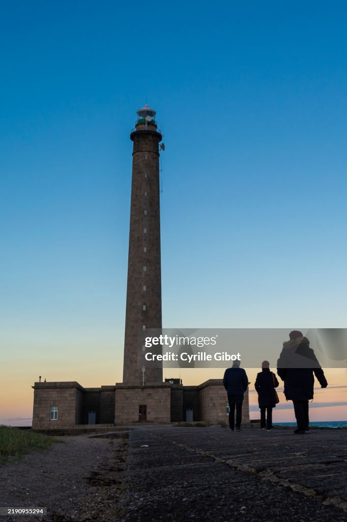 People walking towards the Gatteville lighthouse at sunset, Normandy