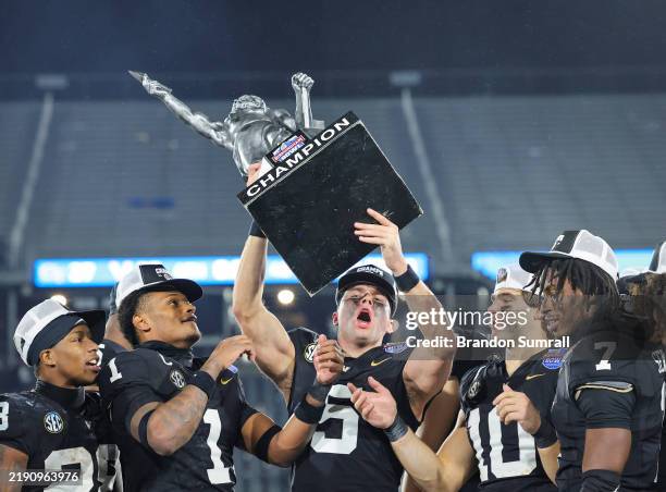 Richie Hoskins of the Vanderbilt Commodores life the Birmingham Bowl Championship Trophy after a win over the Georgia Tech Yellow Jackets at...
