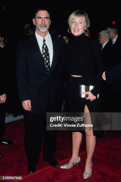 American journalist Phil Bronstein, wearing a black suit over a white shirt with a blue-and-green patterned tie, and his wife, American actress...