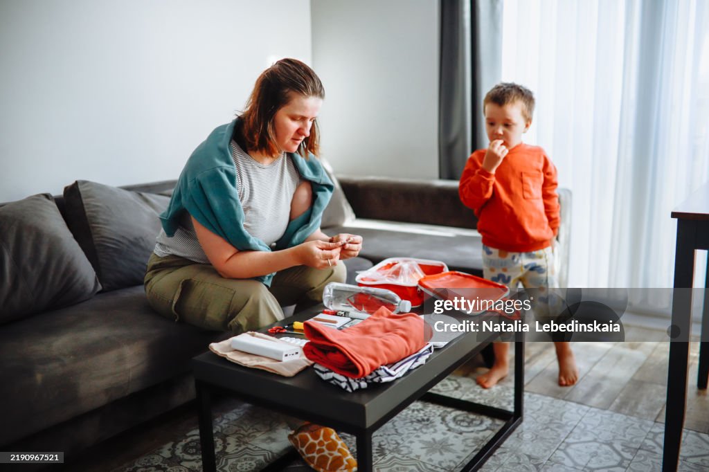 Mom and her toddler review emergency prepping items together in their home living room.