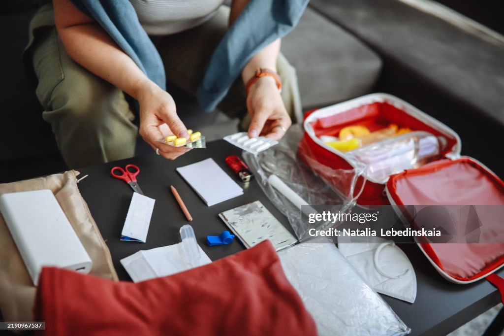 Plus-size unrecognisable woman organizing medicines in a doomsday prepping kit at home, preparing essential supplies for emergencies.