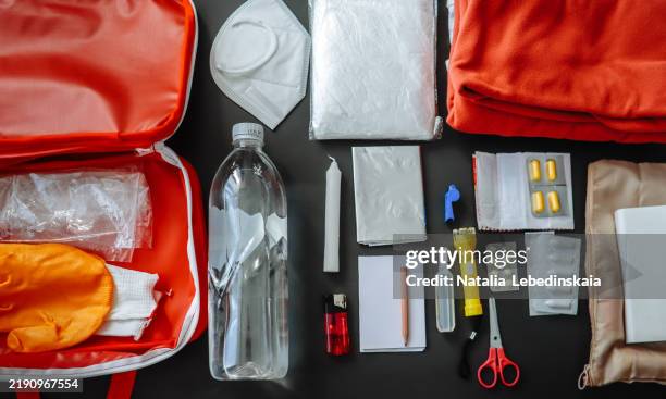 doomsday prepping: water bottle, protective mask, candle, lighter, warm clothing, scissors, packing bags, pills, flashlight. emergency kit, top view in a real home setting. banner top view - first aid kit stock pictures, royalty-free photos & images