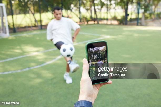 usando un teléfono inteligente, graban en video sus habilidades futbolísticas para contenido de redes sociales. - mensaje de móvil fotografías e imágenes de stock