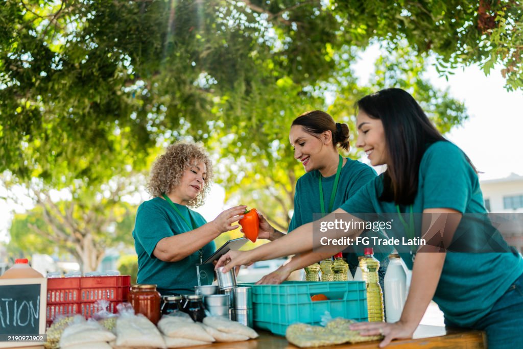 Mature woman talking and organizing donation boxes with volunteers outdoors