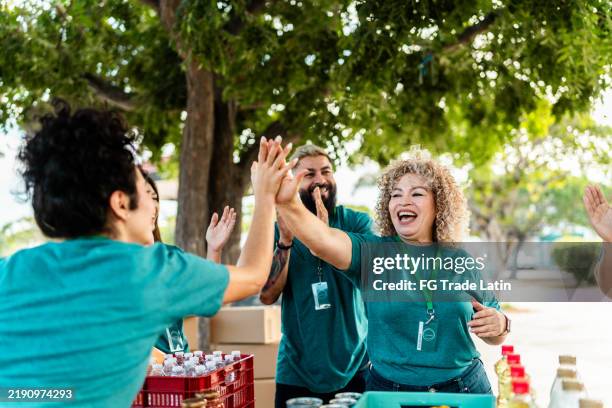 freiwilligenarbeit beim organisieren von spendenboxen und high-fives im freien - gemeinnützige organisation stock-fotos und bilder