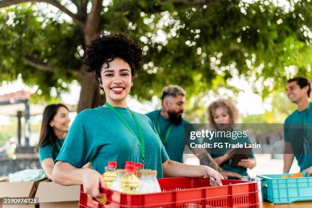 portrait d’une jeune bénévole organisant des boîtes de dons à l’extérieur - altruisme photos et images de collection