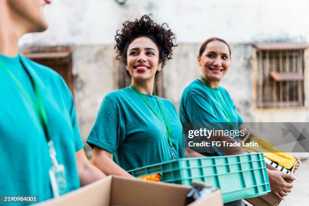 freiwillige beim sprechen und spazierengehen mit spendenboxen im freien - humanitäre hilfe stock-fotos und bilder