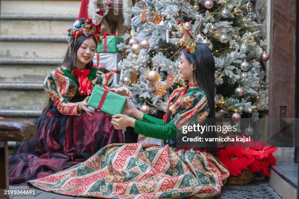 beautiful asian girl in fantasy dress enjoys decorating christmas tree. - 12 17 months stock pictures, royalty-free photos & images