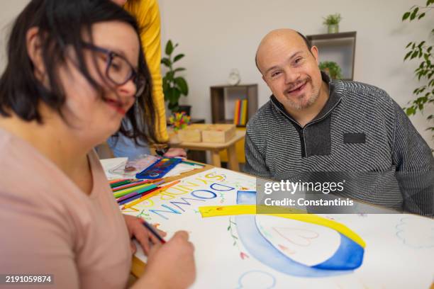 couple with down syndrome exploring creativity through painting - genetic disorder stock pictures, royalty-free photos & images