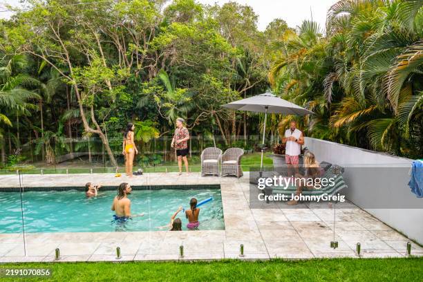 pool party in lush backyard - backyard pool umbrella stock pictures, royalty-free photos & images