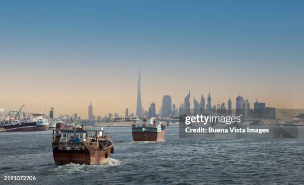 dubai. traditional arabian boats (dhow) and dubai skyline. - gulf countries stock pictures, royalty-free photos & images