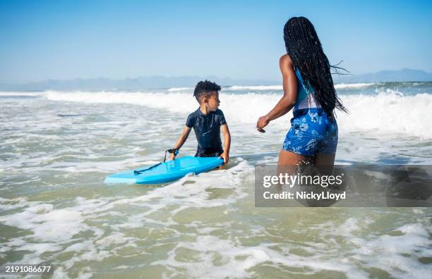 mother and son having fun with bodyboard at beach - boogie board stock pictures, royalty-free photos & images