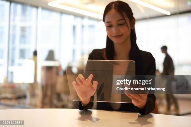 a young professional is utilizing a transparent touchscreen (clear touch screen) to incorporate graphical information within the office environment effectively. - transparent touchscreen display stock pictures, royalty-free photos & images
