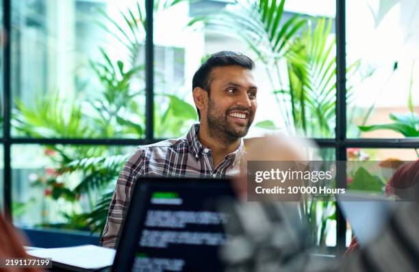 cheerful indian man with beard in business meeting, smiling and listening - technology stock pictures, royalty-free photos & images