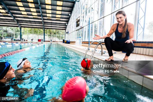 instruktor spricht mit leuten im schwimmkurs - hallenbad stock-fotos und bilder