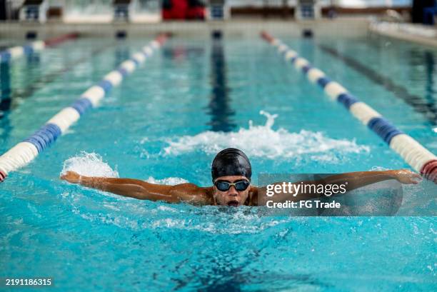 junger mann, schwimmen im schwimmbad - schwimmwettkampf stock-fotos und bilder