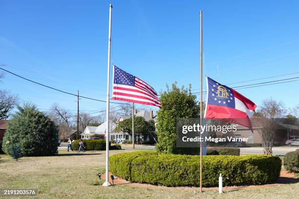 Two flags fly at half mast in the town square as people visit former President Jimmy Carter's home town after he passed away yesterday, on December...