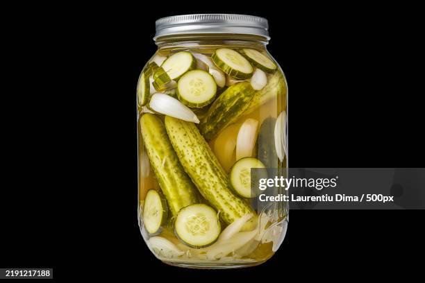 a photo of a glass jar filled with pickled green cucumbers - cetriolino foto e immagini stock
