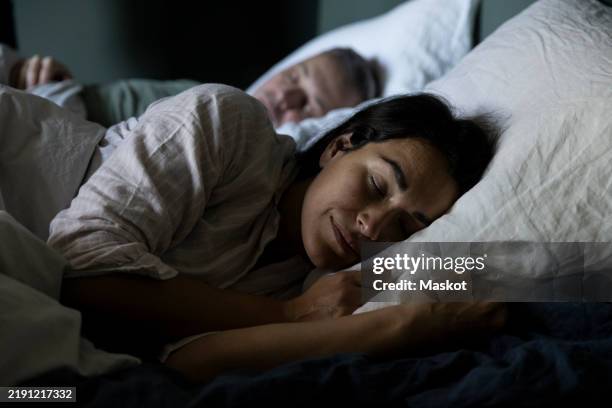 woman sleeping on bed beside man in bedroom at home - slapen stockfoto's en -beelden