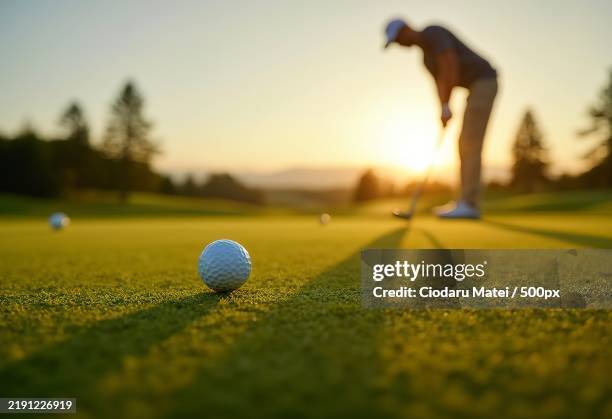 a golf ball on a putting green with a golfers shadow visible in the background - putting golf stock pictures, royalty-free photos & images