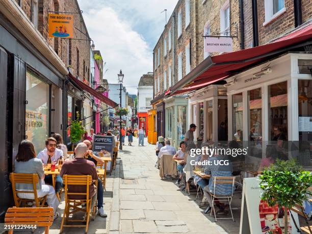 People eating alfresco at restaurant pavement seating in Camden Passage, Islington, London, UK.